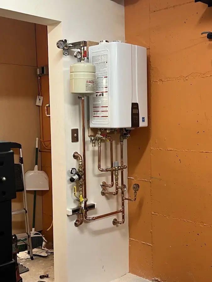 Plumbing technician inspecting water heater connections in New Hampton